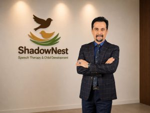 Dr. Azizreza Ghasemzadeh standing in front of the ShadowNest logo in Dubai